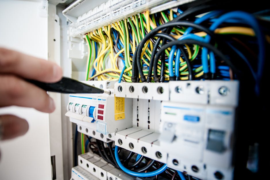 electrician near me Hand of electrician working on a circuit breaker panel with colorful wires, ensuring safe electrical connections.