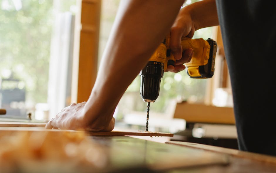 handy man tunbridge wells Close-up of a person using a power drill on wood indoors during daytime.