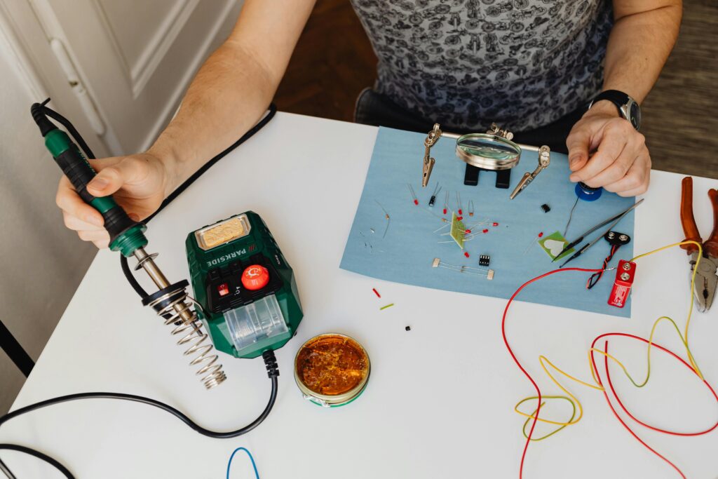 Close-up of a man skillfully soldering electronics with tools on a workbench.